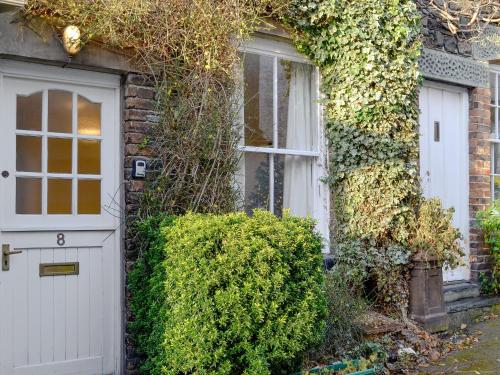 a brick house with a white door and ivy at Jasmine Cottage in Keswick