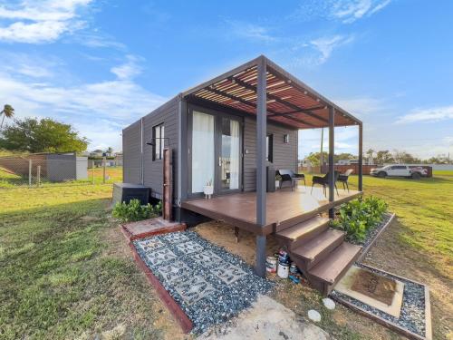 a tiny house with a deck in a field at Casa Andrés Unique Glamping Stay in Isabela in Jobos
