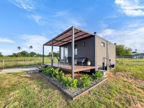 a tiny house with a deck in a field at Casa Andrés Unique Glamping Stay in Isabela in Jobos