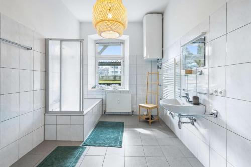a white bathroom with a sink and a tub and a window at Stylische Altbauwohnung Bregenz am See in Bregenz