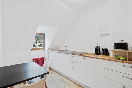 a kitchen with white cabinets and a black table at Villa Seeblick 1908 in Bregenz