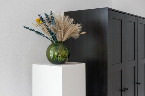 a green vase with flowers on top of a table at Villa Seeblick 1908 in Bregenz