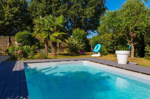 a swimming pool in a yard with a garden at Studio 2-3 personnes piscine partagée in Château-dʼOlonne
