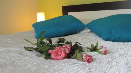 a bouquet of pink roses on a bed with two pillows at Apartament Grey in Iwonicz-Zdrój