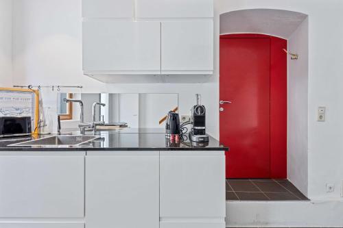 a kitchen with white cabinets and a red door at Villa Seeblick 1908 in Bregenz