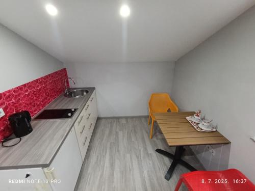 a small kitchen with a wooden table and a red counter top at Apartmani Kula in Tuzla