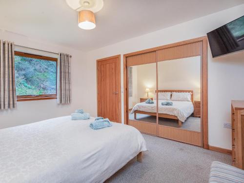 a bedroom with two beds and a large mirror at Balnagowan Mill in Nethy Bridge