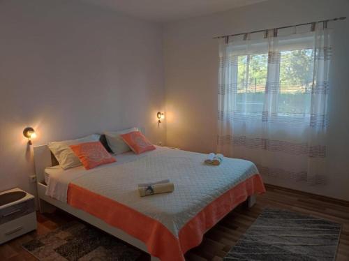 a bedroom with a bed with orange pillows and a window at Apartment Duje Dazlina in Dazlina