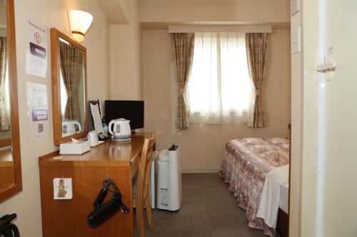 um quarto de hotel com uma cama, uma escrivaninha e uma janela em アイリスイン知立 em Chiryu
