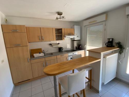 une cuisine avec des armoires en bois et une table en bois dans l'établissement La Résidence St Arnould, À 10 min du centre de Strasbourg, à Schiltigheim