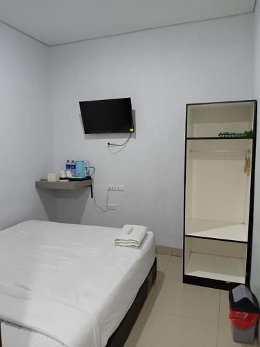 a white room with a bed and a tv at Raja Soeta Express Syariah in Hajimana