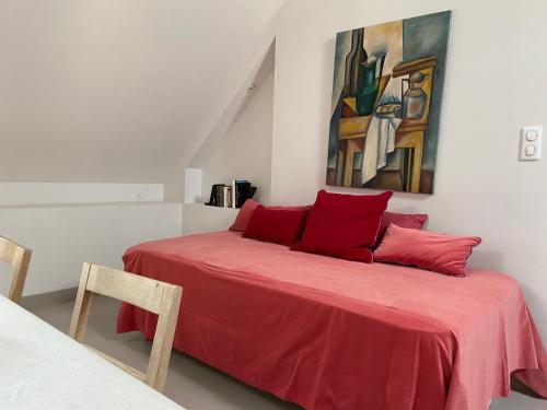 ein Schlafzimmer mit einem roten Bett mit einem Gemälde an der Wand in der Unterkunft Le Loft in Avallon