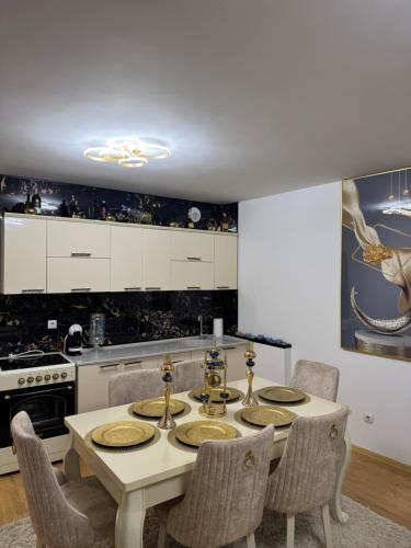 a white kitchen with a table and chairs at Duplex City Center Gjakove in Gjakove