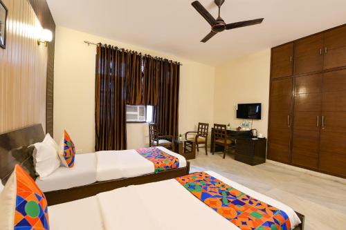 a hotel room with two beds and a desk at FabHotel Next Home Prime in Gurgaon