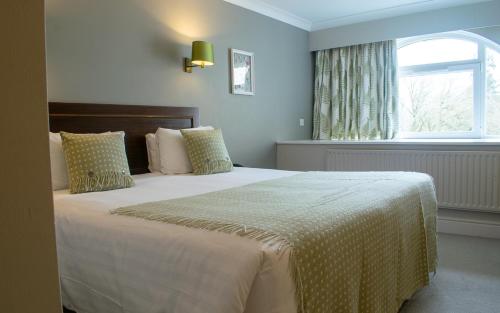 a bedroom with a large bed with a window at Mercure Gloucester Bowden Hall Hotel in Gloucester