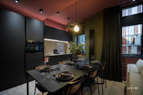 a dining room with a table with chairs and a kitchen at Malva at The Heim in Manchester