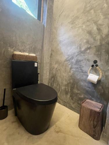 a bathroom with a black toilet and a roll of toilet paper at Drako Villas in Siquijor
