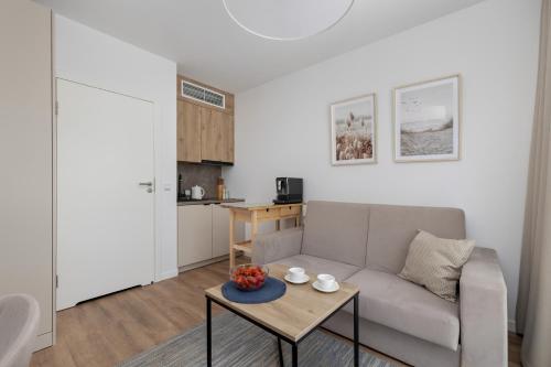 una sala de estar con un sofá y una mesa en Jantaris Apartments near Beach with Fitness by Noclegi Renters, en Mielno