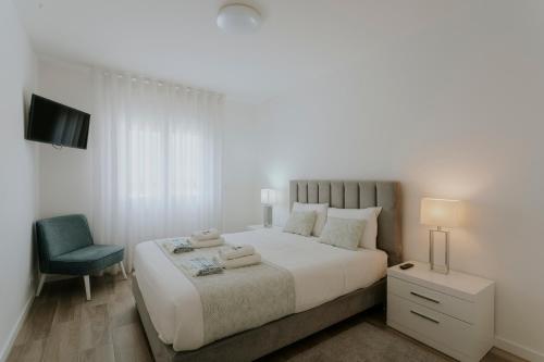 a white bedroom with a bed and a chair at Best Houses 70 - Green Holidays in Serra de El-Rei