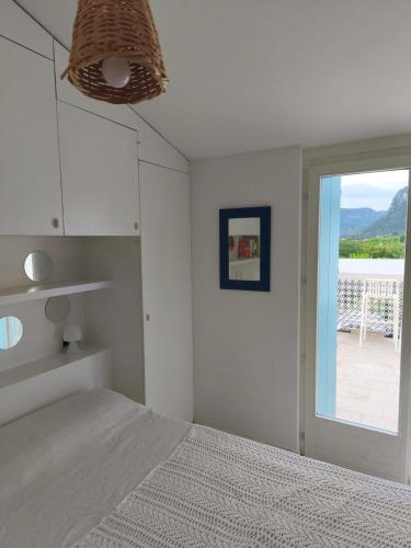 a white bedroom with a bed and a window at Bardolino Blue in Bardolino