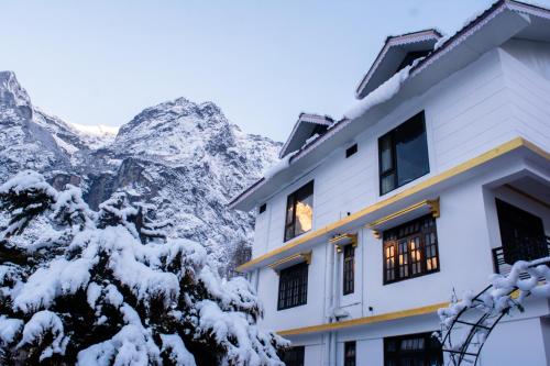 a building with snow covered mountains in the background at Mystique Valley by Trekocity in Lachung