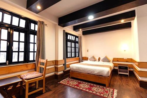 a bedroom with a bed and a desk and windows at Mystique Valley by Trekocity in Lachung