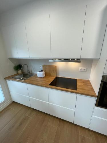 Apartamento PLAYA DE SALGUEIRON في كانجاس دي مورازو: مطبخ بخزائن بيضاء ومغسلة