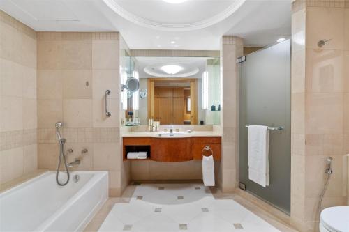 a bathroom with a tub and a shower and a sink at Makati Shangri-La, Manila in Manila