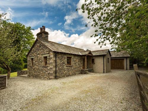 an old stone house with a garage on a gravel driveway at 1 Bed in Coniston LCC50 in Coniston