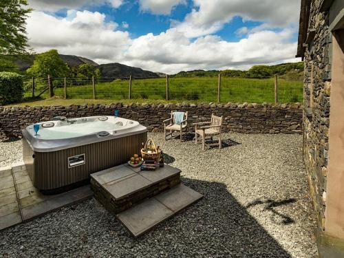 a bath tub sitting in a yard next to a stone wall at 1 Bed in Coniston LCC50 in Coniston