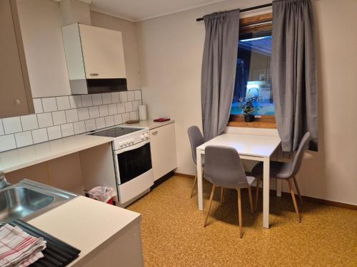 una piccola cucina con tavolo, sedie e finestra di Leilighet Åmdals Verk, Telemark a Åmdals Verk