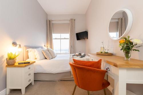 a bedroom with a bed with a desk and a mirror at The Clarence Gardens Hotel, BW Signature Collection in Scarborough