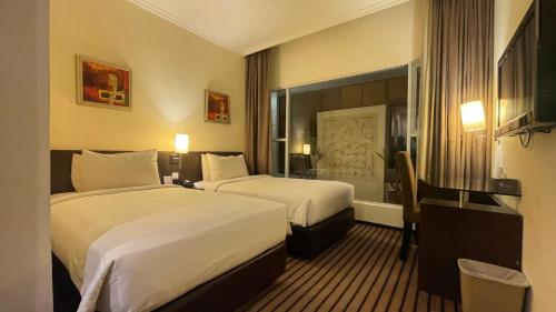 a hotel room with two beds and a desk at Harmoni One Convention Hotel and Service Apartments in Batam Center