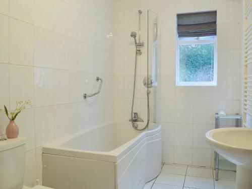 a white bathroom with a tub and a sink at Sheilings in Elterwater