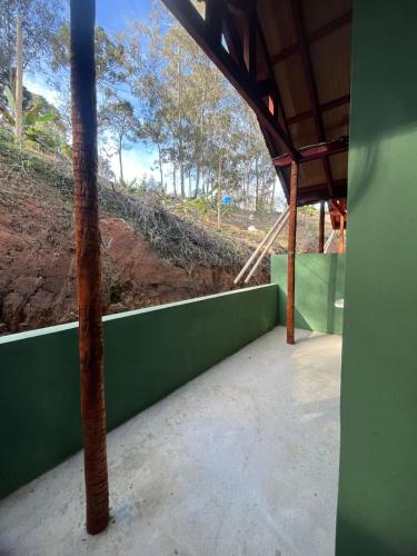 a room with a green wall and a pole at Chalés do vale Extrema verde in Extrema