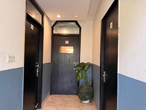a hallway with two black doors and a potted plant at Hotel Hauz Khas Inn Near Hauz Khas Fort and Deer Park in New Delhi