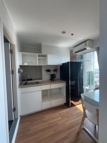 a kitchen with white cabinets and a table in a room at Minimalist Condo in Pinklao in Bangkok