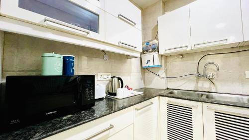 a kitchen with a microwave and a black counter top at BluO 3BHK Safdarjung Enclave, Lift & Terrace Garden in New Delhi