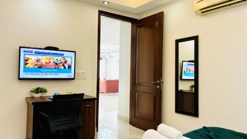a living room with a television on a wall at Olive Service Apartments Safdarjung Enclave in New Delhi
