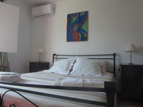 a bedroom with a bed with a painting on the wall at Casa Eira do Povo in Vale de Colmeias