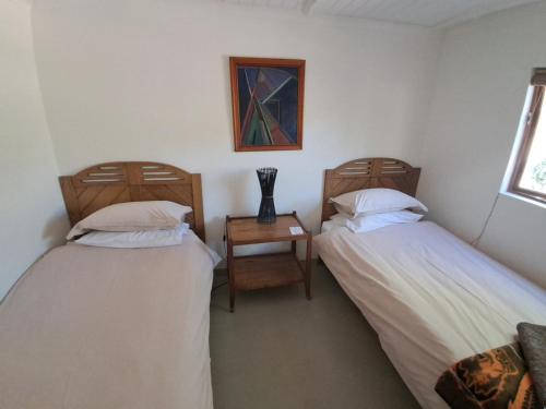 two beds in a room with a table and a chair at Kleinwatervalplaas Farm Stay Accomodation in Caledon