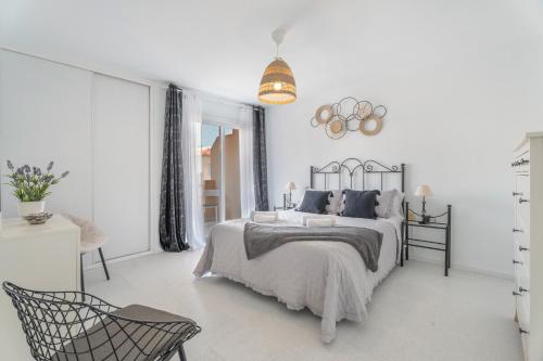 a white bedroom with a bed and a chair at Apartamento Afirama 1 in Araya