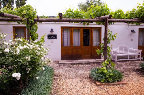 a house with a wooden door and a bench outside at Vygeboom Studio in Nieu-Bethesda