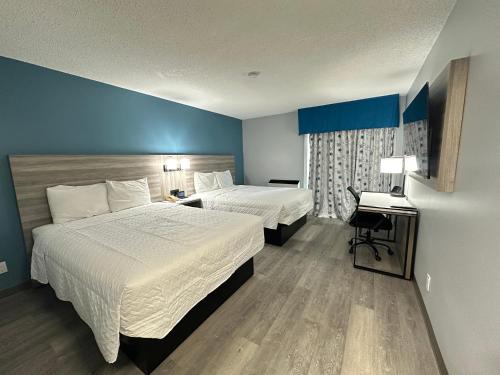 a hotel room with two beds and a desk at Travelodge by Wyndham Bracebridge in Bracebridge