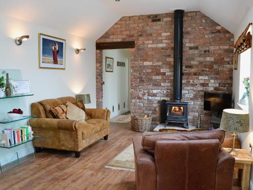 a living room with two couches and a fireplace at Wheatsheaf Cottage in Nun Monkton