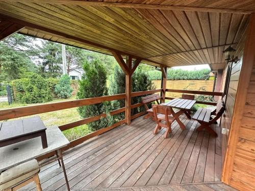 a wooden deck with a table and benches on it at Noclegi na Szczęśliwej 1 w Okunince in Okuninka