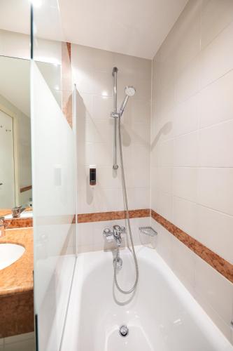 a bathroom with a shower and a white tub at ACHAT Hotel Magdeburg in Magdeburg