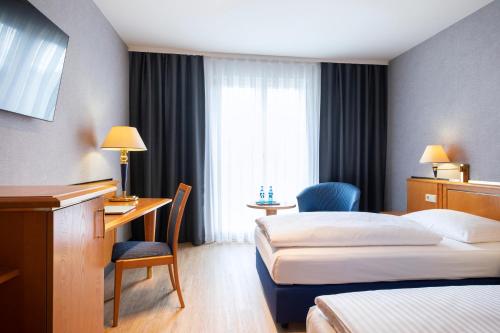 a hotel room with two beds and a desk and a desk at ACHAT Hotel Magdeburg in Magdeburg