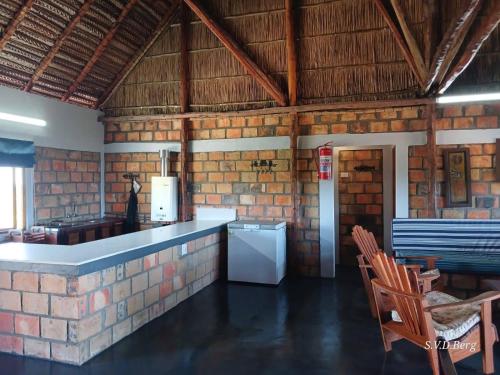 a kitchen with a white refrigerator and a brick wall at Villa Dorado in Cabo Guinjata
