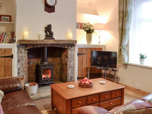 ein Wohnzimmer mit Kamin, Tisch und Fernseher in der Unterkunft Rhona's Cottage in Abergavenny
